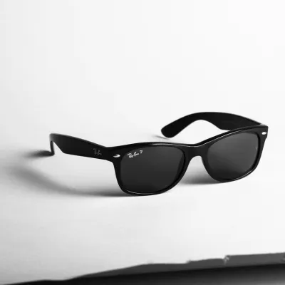 A pair of black Ray-Ban frames on a paper background