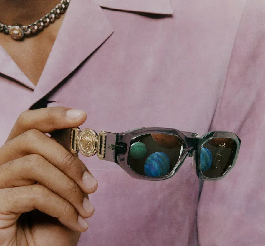 A woman in a blazer adjusting sunglasses on her face